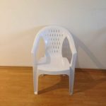 Sedia in resina bianca con braccioli.